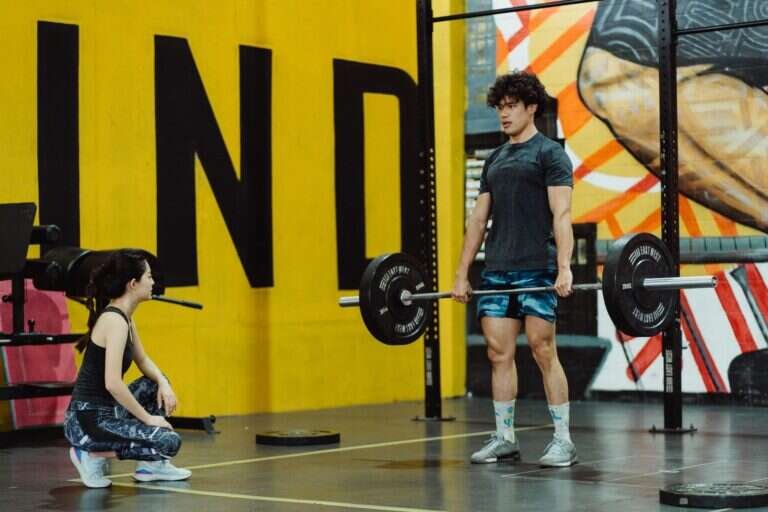 Man performing a deadlift with a coach observing his form