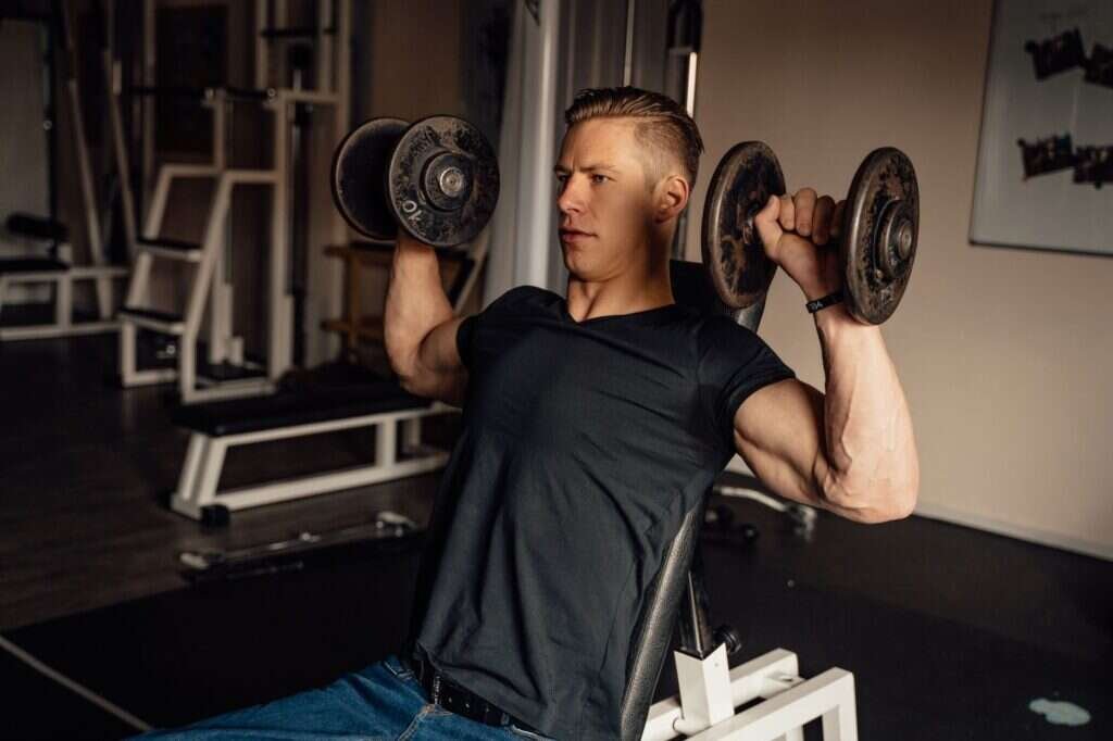 Man performing a dumbbell shoulder press during a strength training session