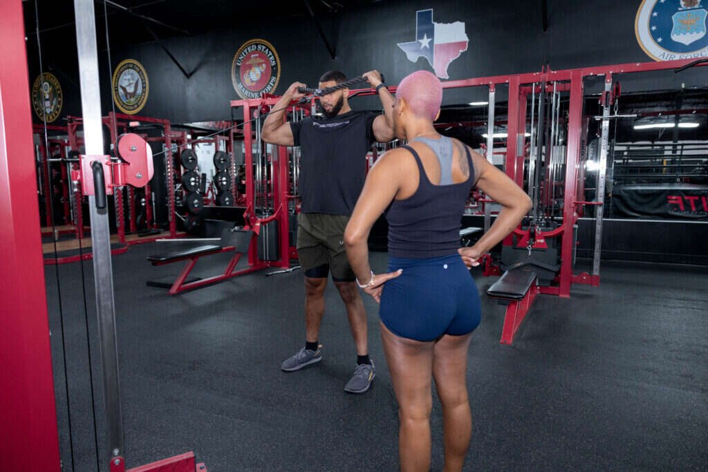 Personal trainer demonstrating a cable rope exercise for the shoulders at Gryffon Performance in Dallas