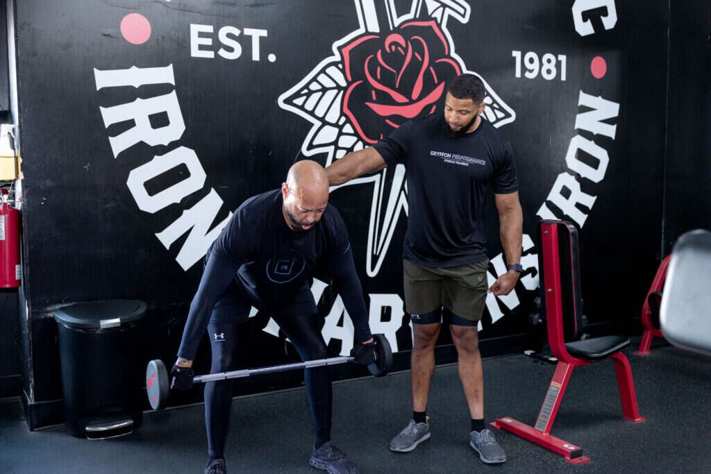 Personal trainer guiding a barbell hip hinge at Gryffon Performance in Dallas