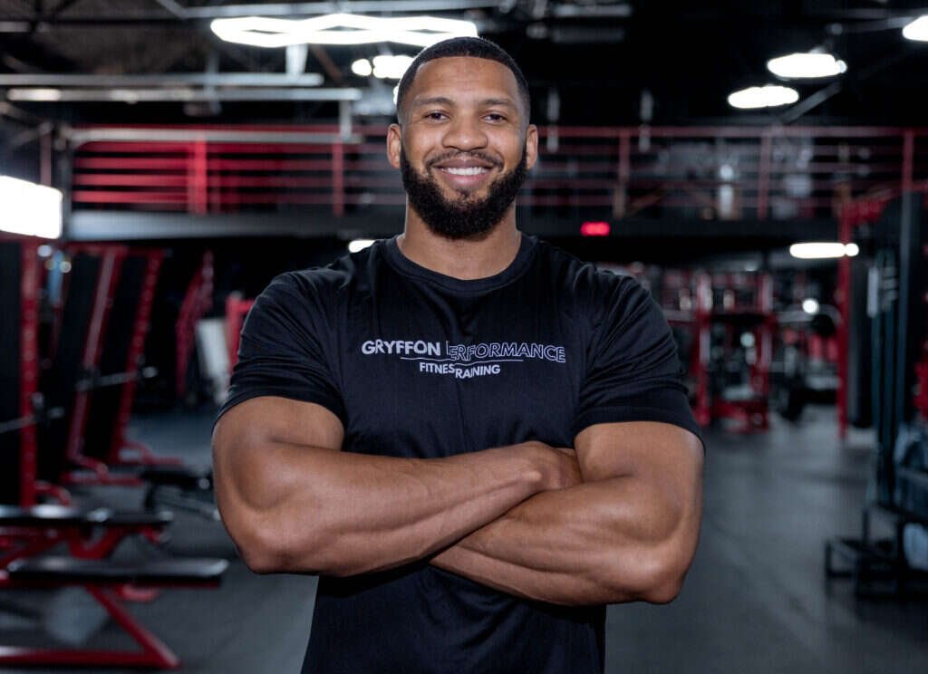 Gryffon Performance personal trainer, arms crossed, on the training floor of the private studio in Dallas