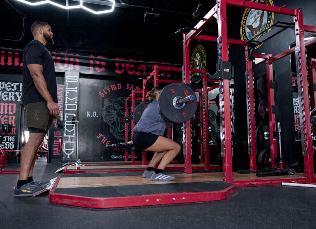 Barbell squat with a personal trainer watching at Gryffon Performance in Dallas